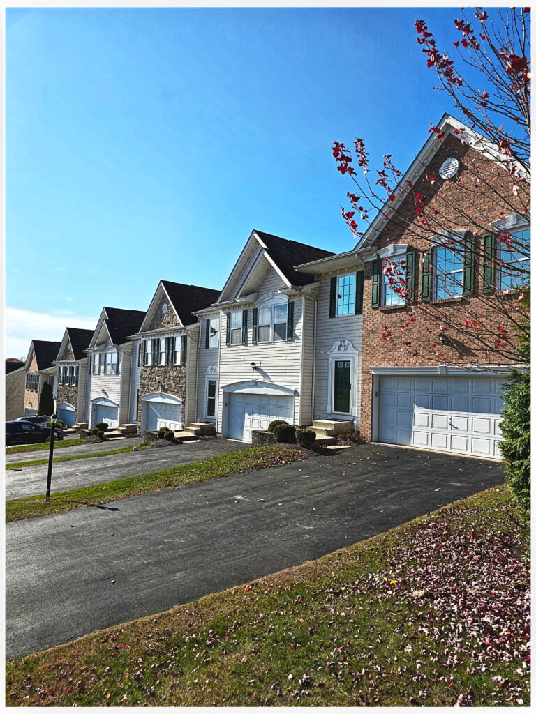 Tan and brick townhome row exterior with white garage doors, Peters Township PA
