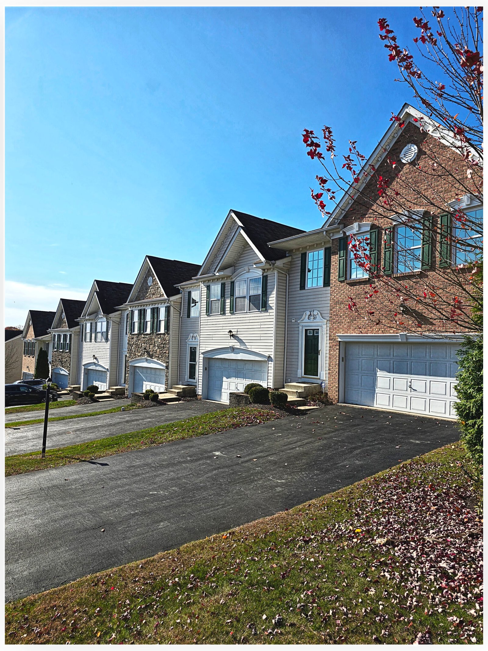 Tan and brick townhome row exterior with white garage doors, Peters Township PA
